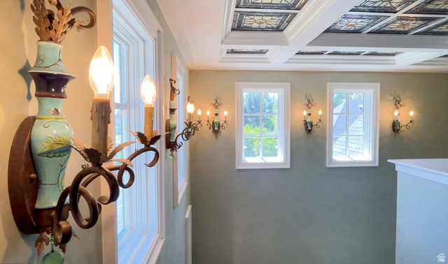 426 West Center Street Parowan, UT 84761 - Photo 45 of 107 Ornate sconces illuminate a hallway featuring multiple windows, a coffered ceiling with decorative panels, and a painted wall finish