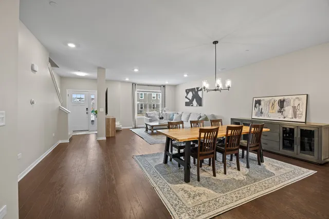 a view of a dining room and livingroom with furniture wooden floor a rug a flat screen tv a rug and a chandelier