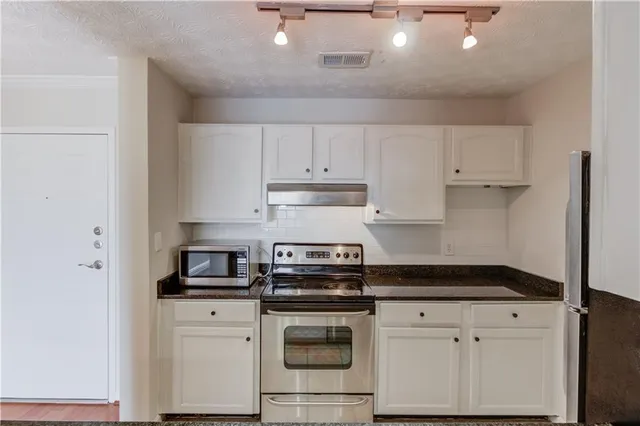 a kitchen with white cabinets and stainless steel appliances