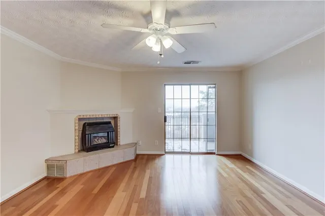 an empty room with windows a fireplace and wooden floor