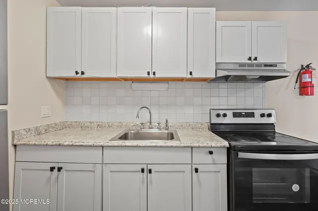 a kitchen with granite countertop white cabinets and a stove