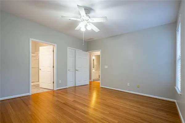 an empty room with wooden floor and ceiling fan