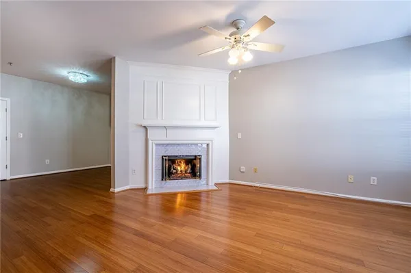 a view of an empty room with wooden floor and a fireplace