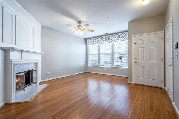 a view of an empty room with wooden floor fireplace and a window