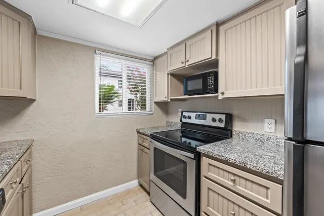 a kitchen with granite countertop cabinets stainless steel appliances and a window