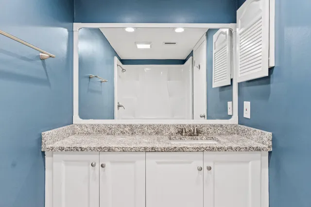 a bathroom with a granite countertop sink and a mirror