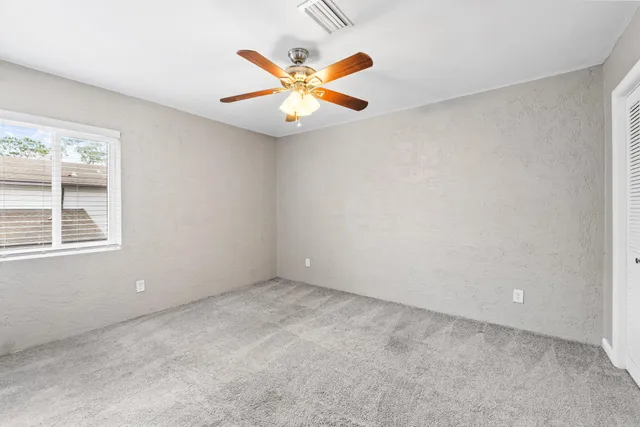 an empty room with a window and a fan