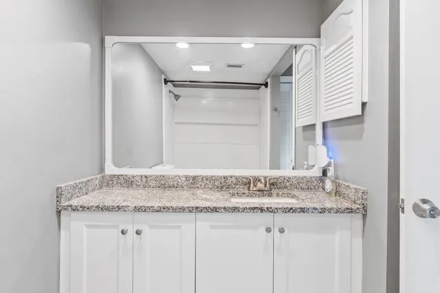 a bathroom with a granite countertop sink and a mirror