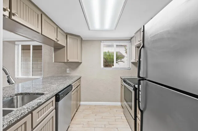 a kitchen with granite countertop a sink appliances cabinets and a window