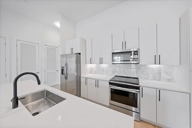 a kitchen with granite countertop a stove a sink and refrigerator