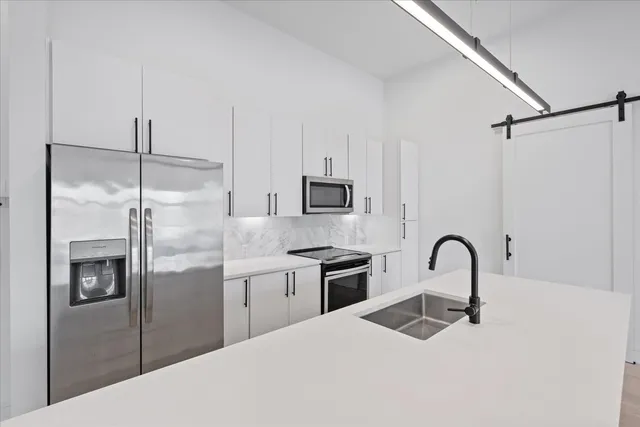 a kitchen with stainless steel appliances kitchen island a refrigerator sink and cabinets