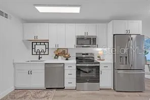 a kitchen with cabinets stainless steel appliances and a counter space