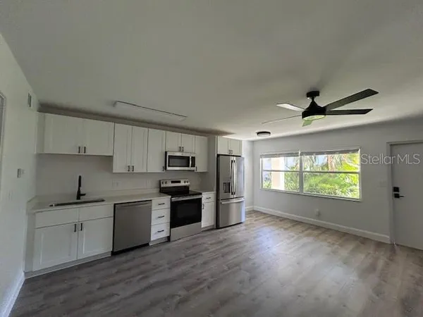 a kitchen with stainless steel appliances a sink a stove a refrigerator cabinets and a window