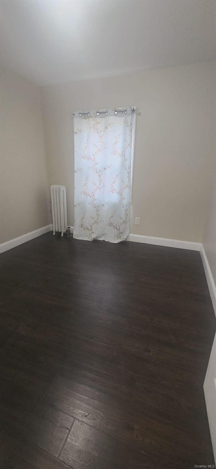 108-24 Springfield Boulevard Queens, NY 11429 - Photo 2 of 10 Empty room with dark wood finished floors and radiator heating unit