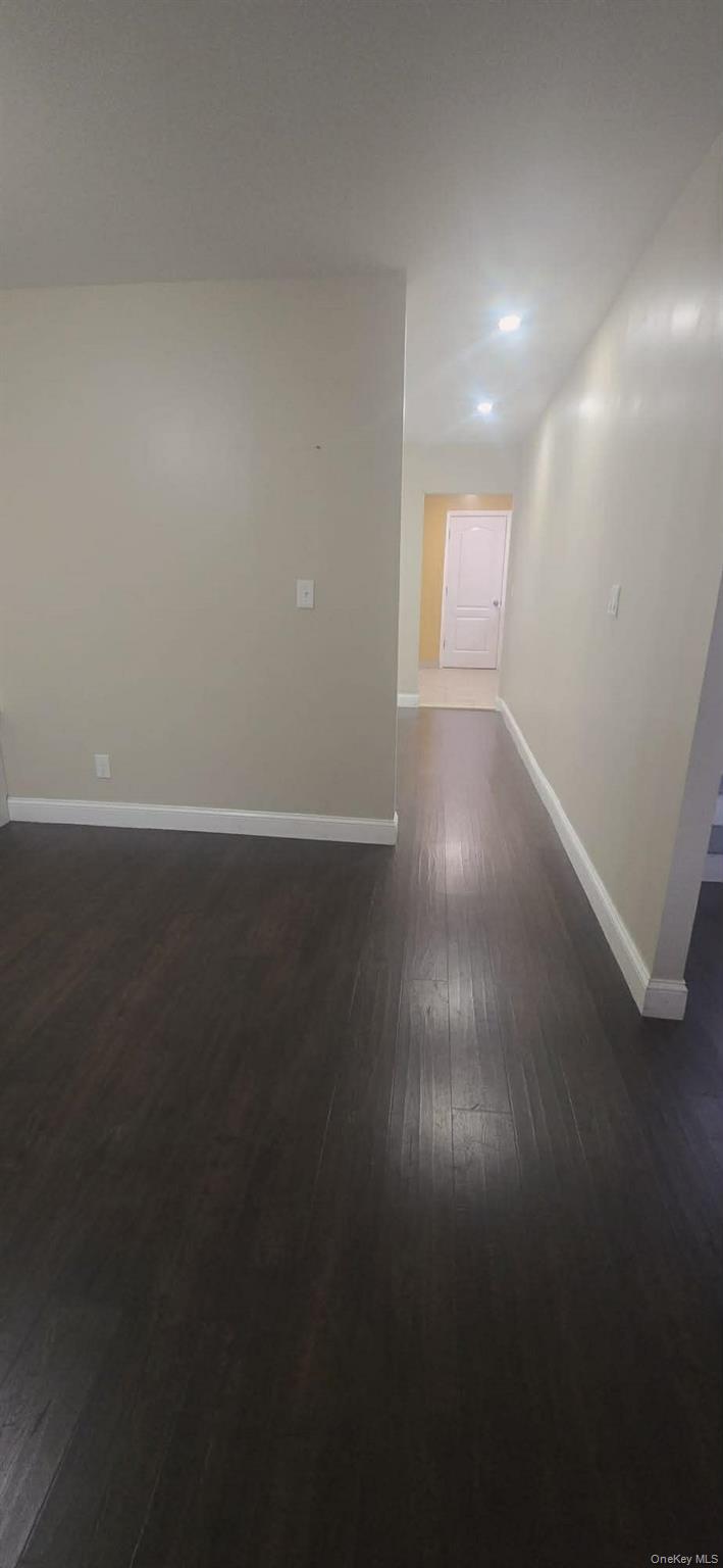108-24 Springfield Boulevard Queens, NY 11429 - Photo 3 of 10 Unfurnished room with baseboards and dark wood-style floors