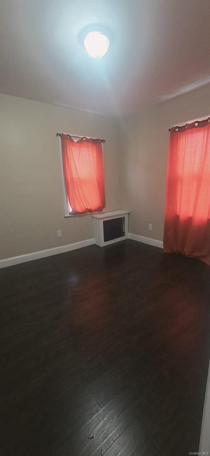 108-24 Springfield Boulevard Queens, NY 11429 - Photo 4 of 10 Empty room featuring baseboards and dark wood-style floors