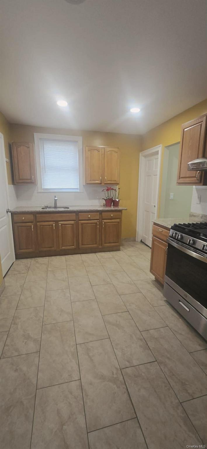 108-24 Springfield Boulevard Queens, NY 11429 - Photo 5 of 10 Kitchen featuring stainless steel gas range oven, light countertops, recessed lighting, and brown cabinets