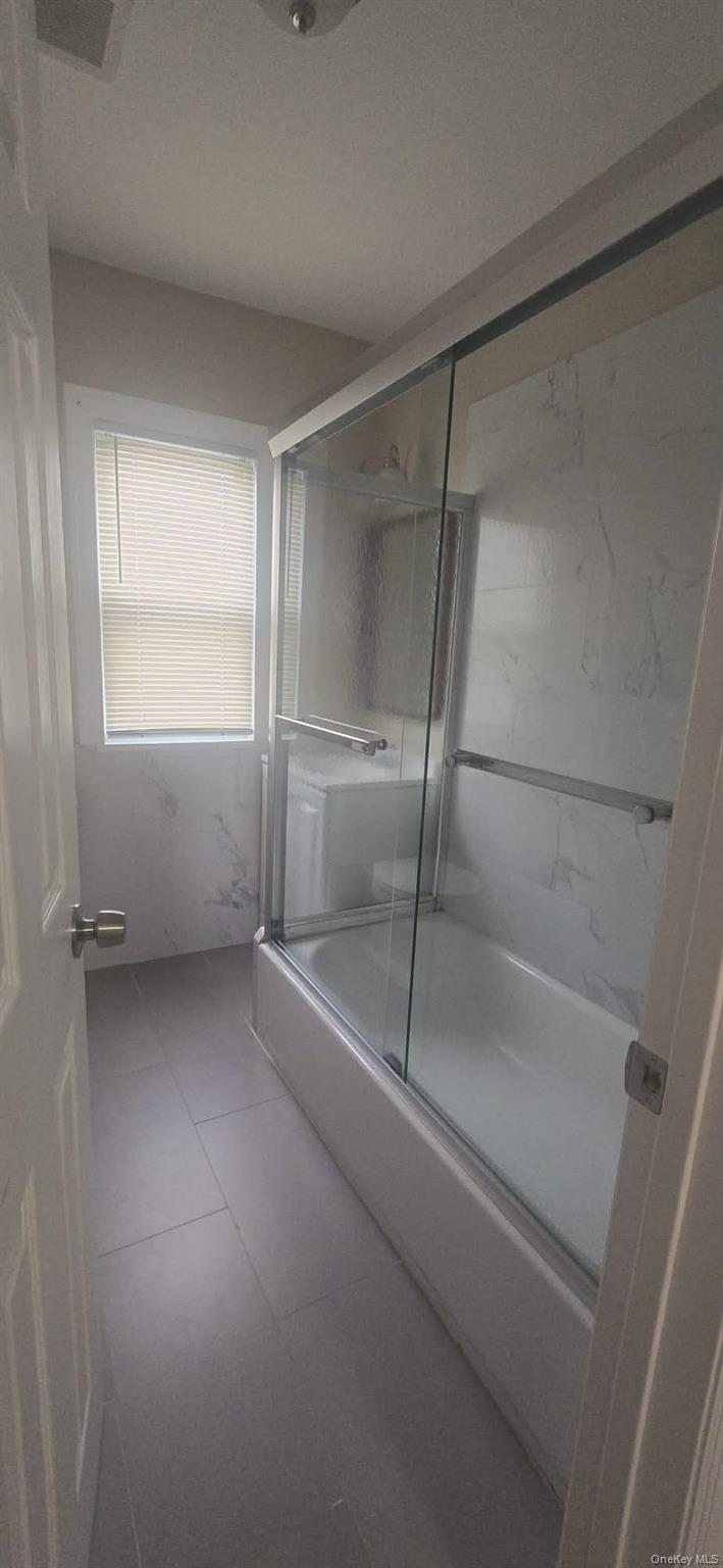 108-24 Springfield Boulevard Queens, NY 11429 - Photo 10 of 10 Full bath with shower / bath combination with glass door and tile patterned floors