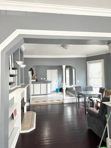 a living room with couches and a dining table with wooden floor