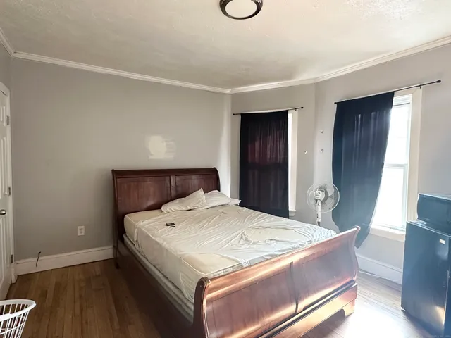 a bedroom with a bed and wooden floor