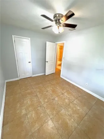 an empty room with a chandelier fan and windows