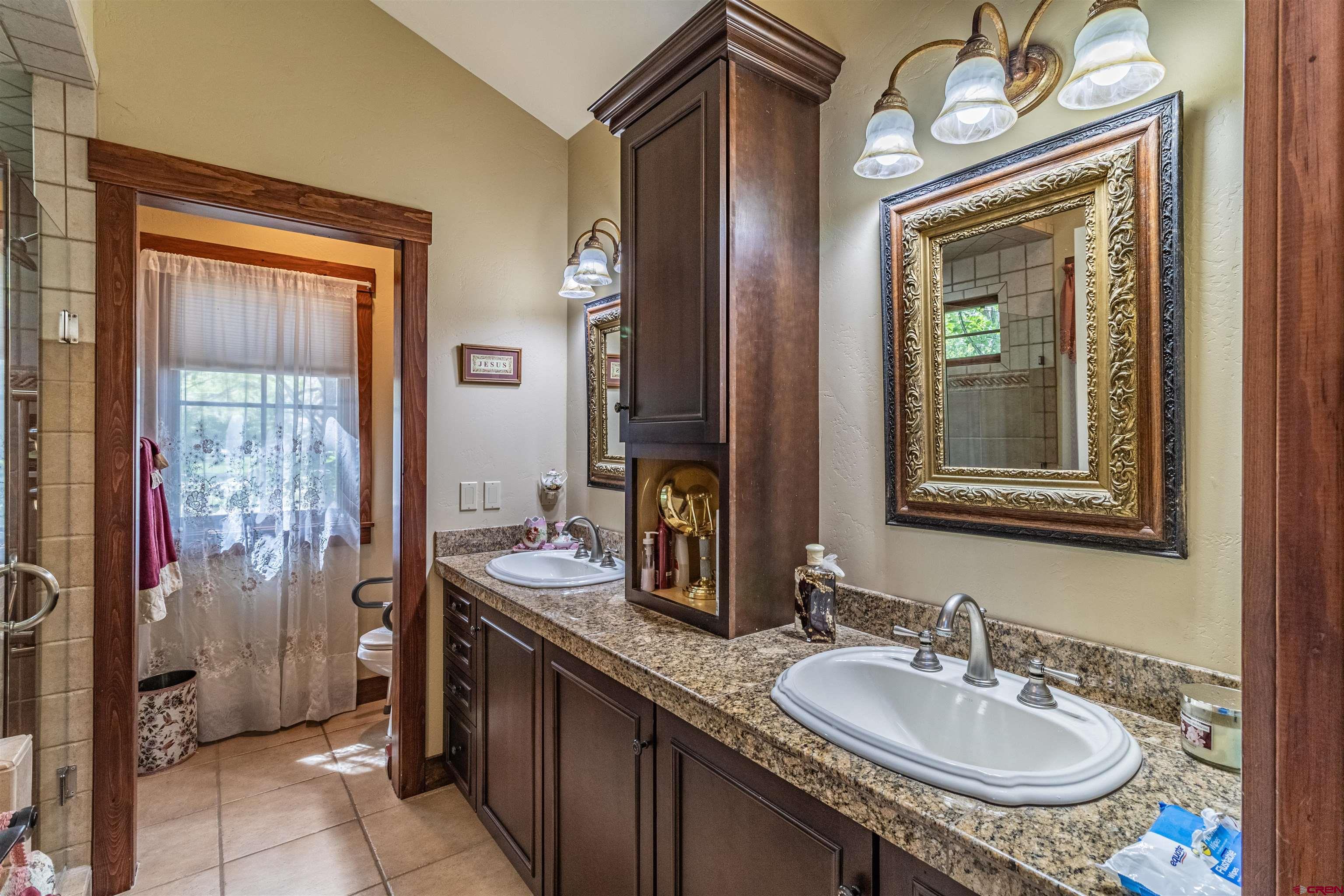 1167 North Dalton Ranch Road Durango, CO 81301 - Photo 19 of 45 a bathroom with a granite countertop sink a mirror and a shower