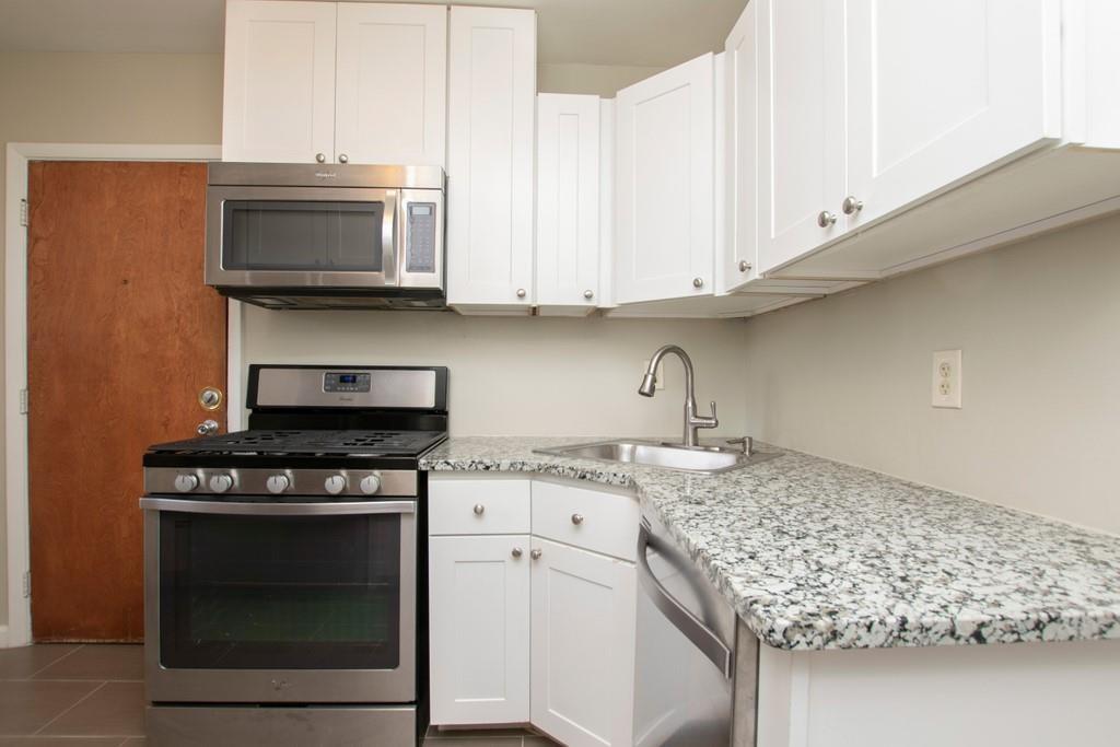 a kitchen with granite countertop a stove top oven microwave and cabinets