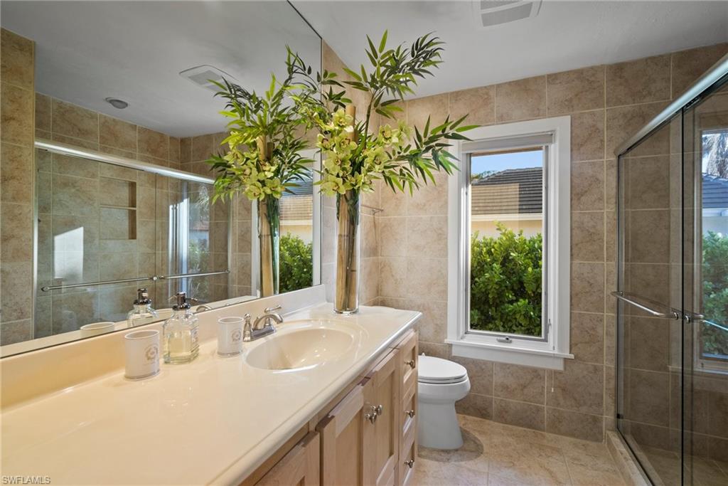 319 Pirates Bight Naples, FL 34103 - Photo 22 of 26 a bathroom with a granite countertop sink a toilet and a shower