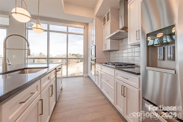 a large kitchen with kitchen island a large window cabinets a sink and stainless steel appliances