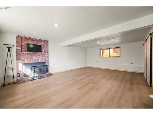 a view of empty room with wooden floor and fireplace