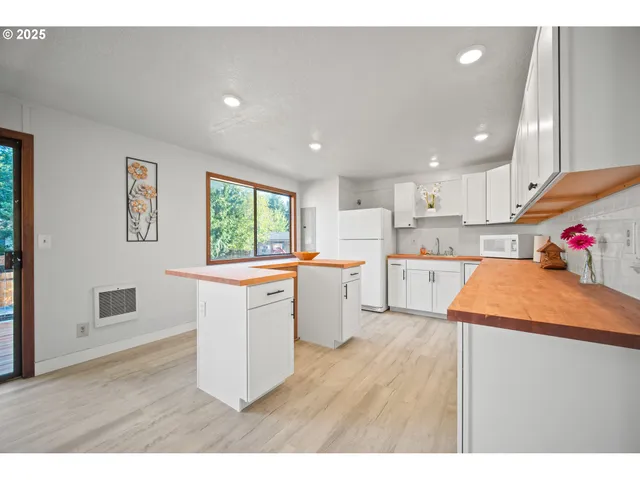 a open kitchen with white cabinets and wooden floor