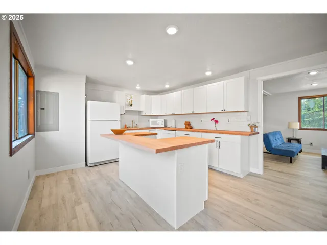 a kitchen with stainless steel appliances kitchen island sink refrigerator and wooden floor
