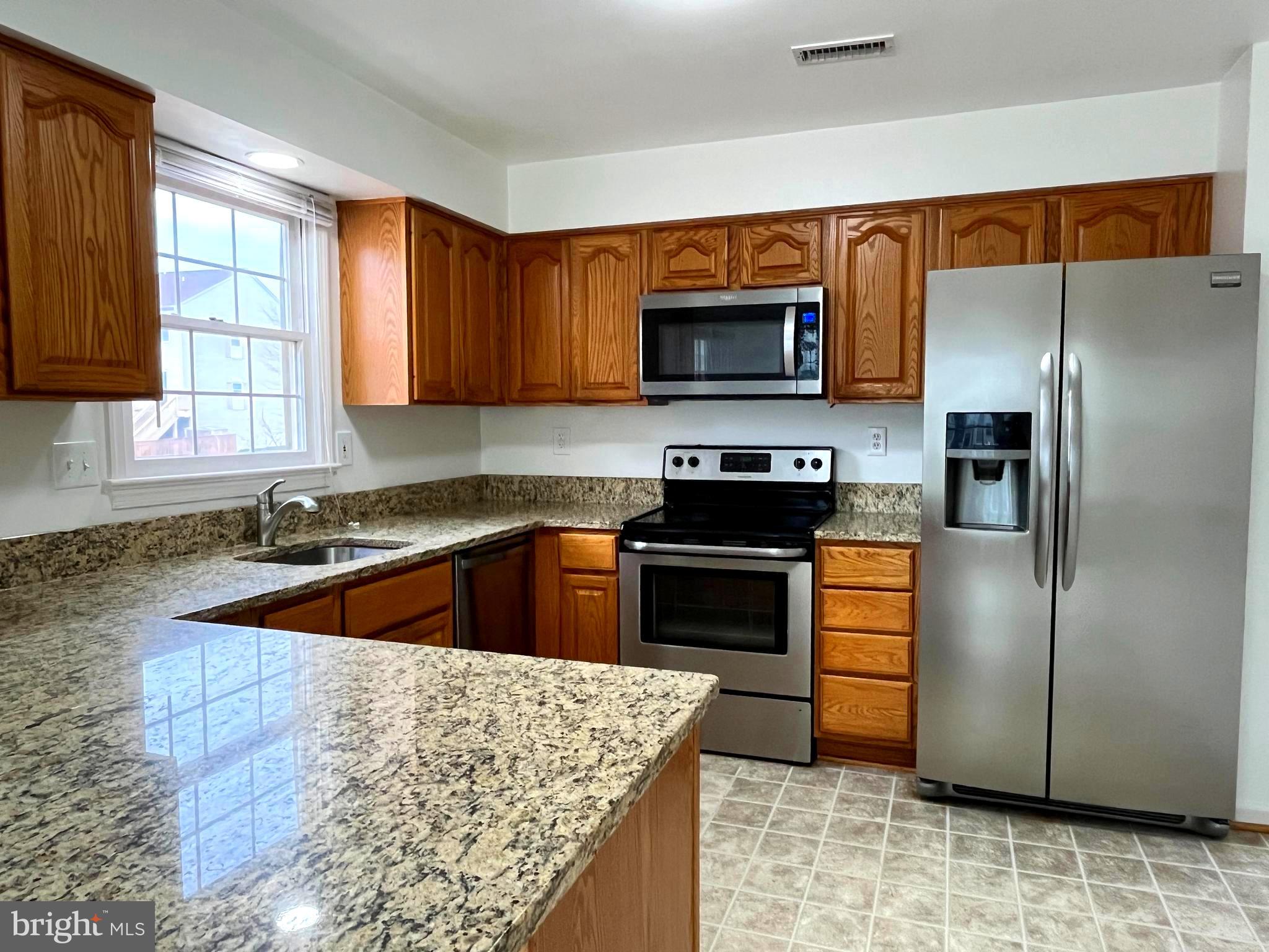 2034 Pinecroft Court Odenton, MD 21113 - Photo 4 of 31 a kitchen with stainless steel appliances granite countertop a refrigerator a stove and a sink with wooden cabinets