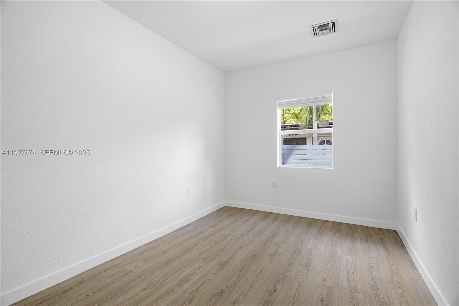 465 Northeast 165th Street, Unit 465 Miami, FL 33162 - Photo 13 of 15 an empty room with wooden floor and windows