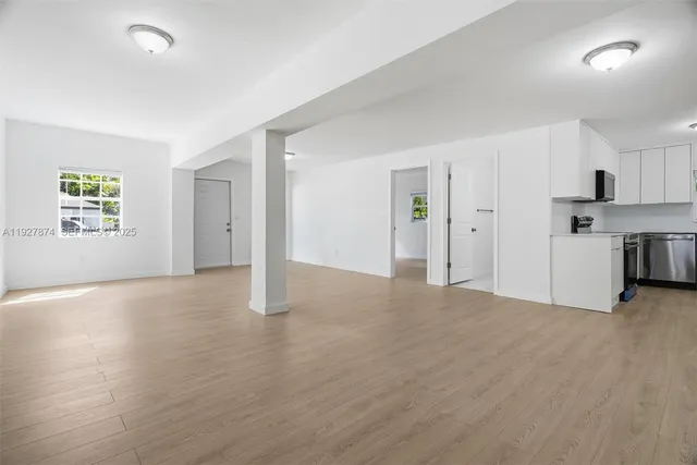 a view of empty room with kitchen and window