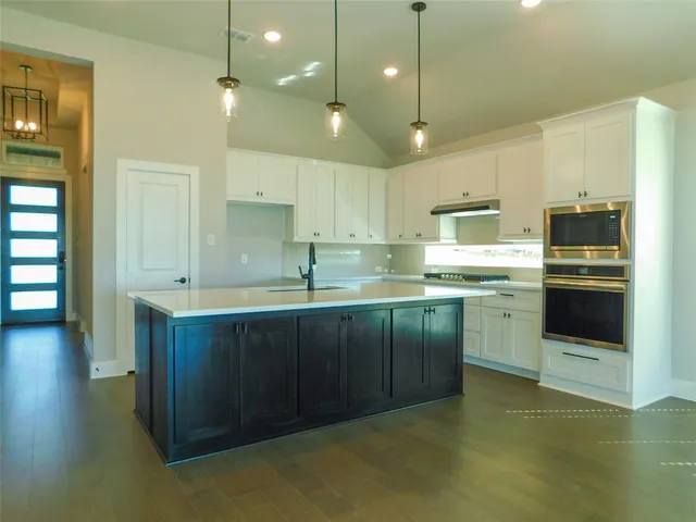 a kitchen with stainless steel appliances granite countertop a sink a stove a refrigerator and a oven with wooden floor