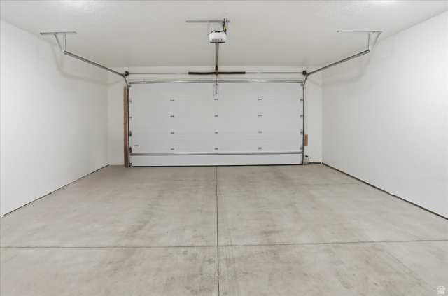 1838 West 300th Street South, Unit B Mapleton, UT 84664 - Photo 32 of 51 Spacious garage featuring a concrete floor, bright white walls, and an automatic overhead door system