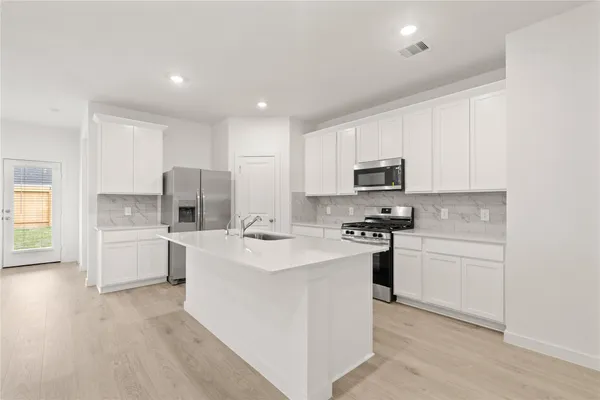 a kitchen with white cabinets and stainless steel appliances