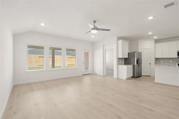 a view of an empty room with kitchen and a window