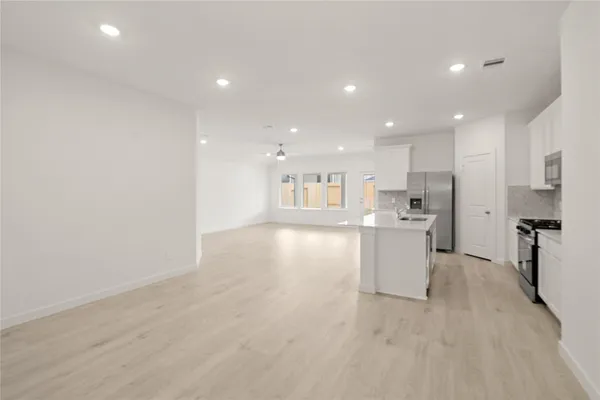 a view of kitchen with center island wooden floor stainless steel appliances and cabinets
