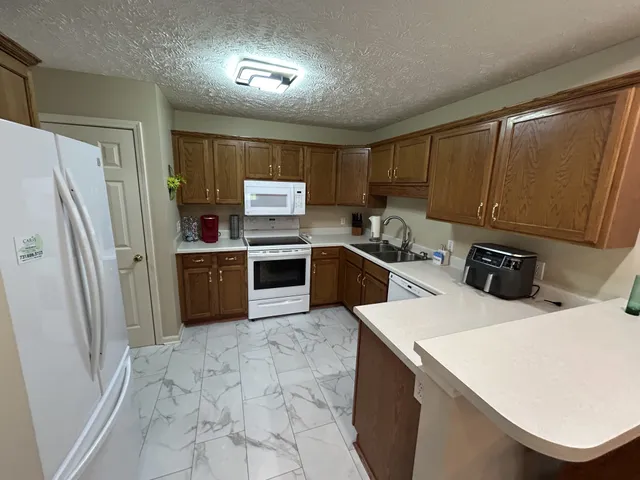 a kitchen with stainless steel appliances a sink a stove a refrigerator cabinets and a window