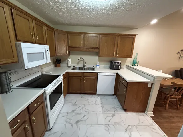 a kitchen with a sink a stove top oven a refrigerator cabinets and a window