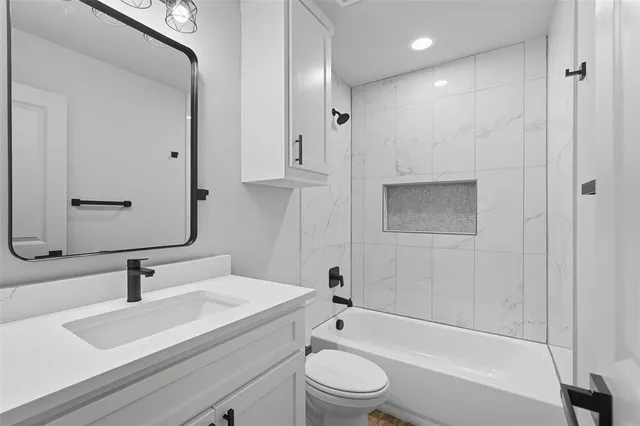 a bathroom with a bathtub shower sink vanity and toilet