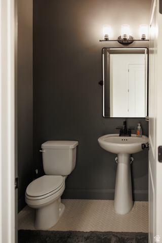 629 Spring Lily Drive St. George, UT 84790 - Photo 19 of 50 Compact lavatory featuring a white pedestal sink with a matte black faucet, a rectangular mirror, and a three-light vanity fixture