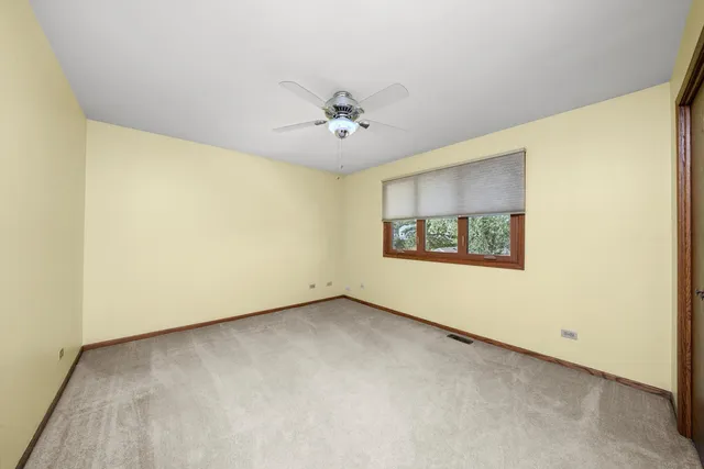 an empty room with windows and ceiling fan
