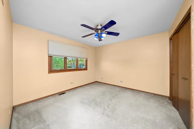 an empty room with windows and ceiling fan