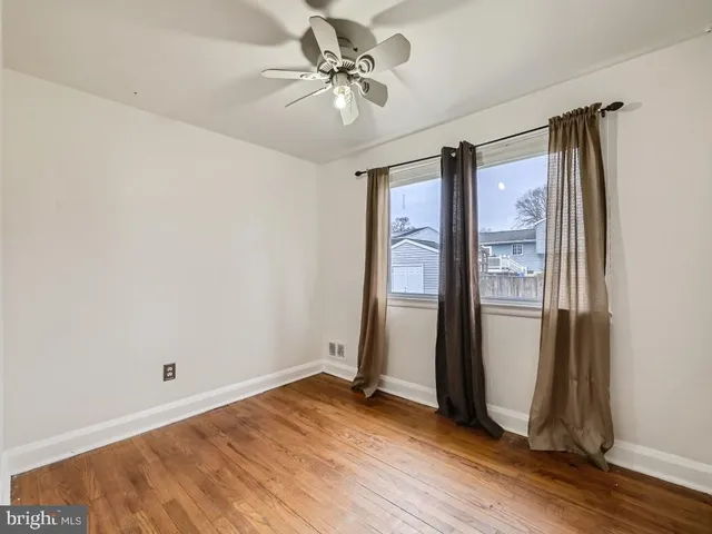 an empty room with wooden floor and a ceiling fan