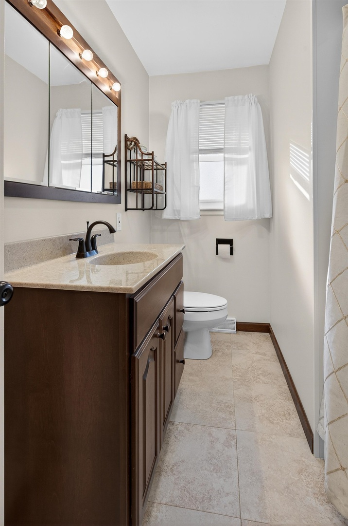 1136 4th Avenue North Clinton, IA 52732 - Photo 13 of 34 a bathroom with a granite countertop sink a toilet and a mirror