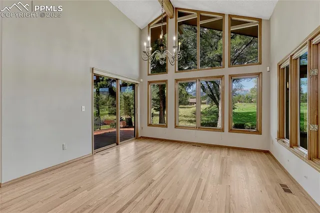 an empty room with wooden floor view and windows