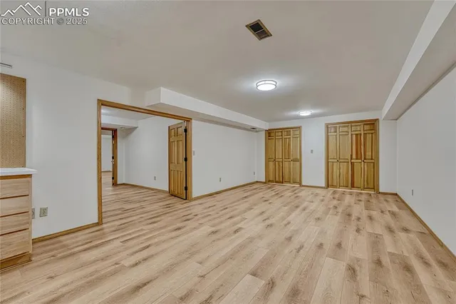 a view of an empty room with wooden floor and closet